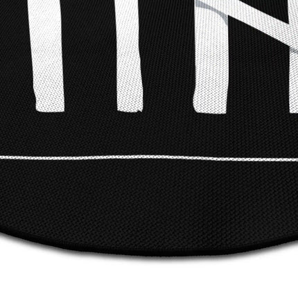 Close up of burnt matches graphic round rug Jet Black edge showing woven polyester detail