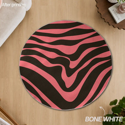 Overhead view of a round bone white-edged custom rug printed with a pink and black wavy zebra-stripe pattern, placed on a wood floor.