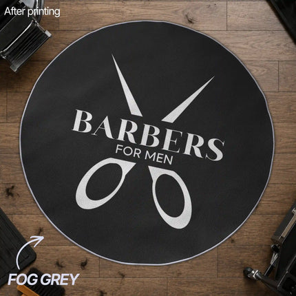 Overhead view of a round fog grey custom rug with a black-and-white 'Barbers for Men' scissors logo design, placed on a wood floor in a barbershop setting.