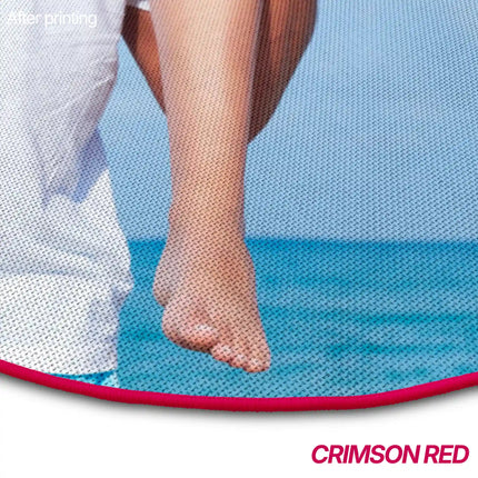 Close-up of a round rug's crimson red piped edge showing part of a printed beach photo with people's legs and feet against a blue background.