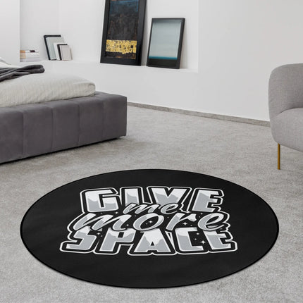 Black typography graphic round rug with “Give Me More Space” text styled in a modern bedroom with Jet Black edge