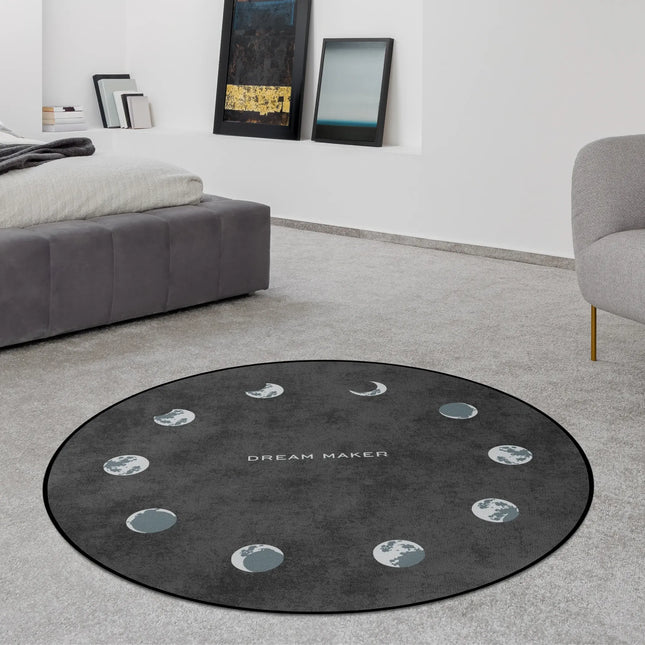 Lunar cycle graphic round rug with moon phase artwork and Dream Maker typography styled in a modern bedroom with Jet Black edge finish