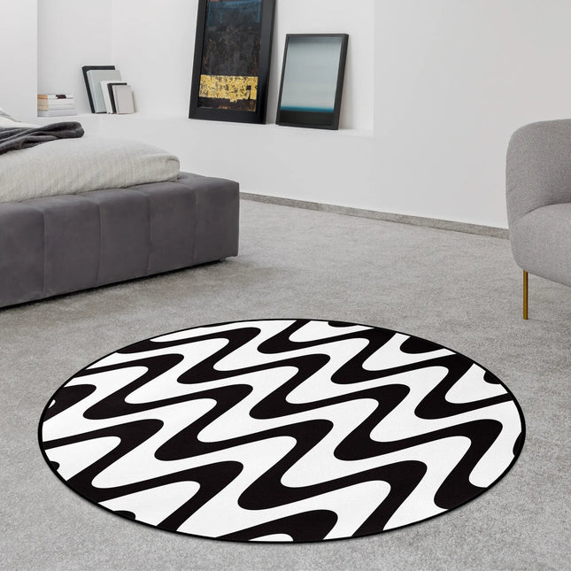 Static flow graphic round rug with bold black and white wave pattern styled in a modern bedroom with Jet Black edge finish